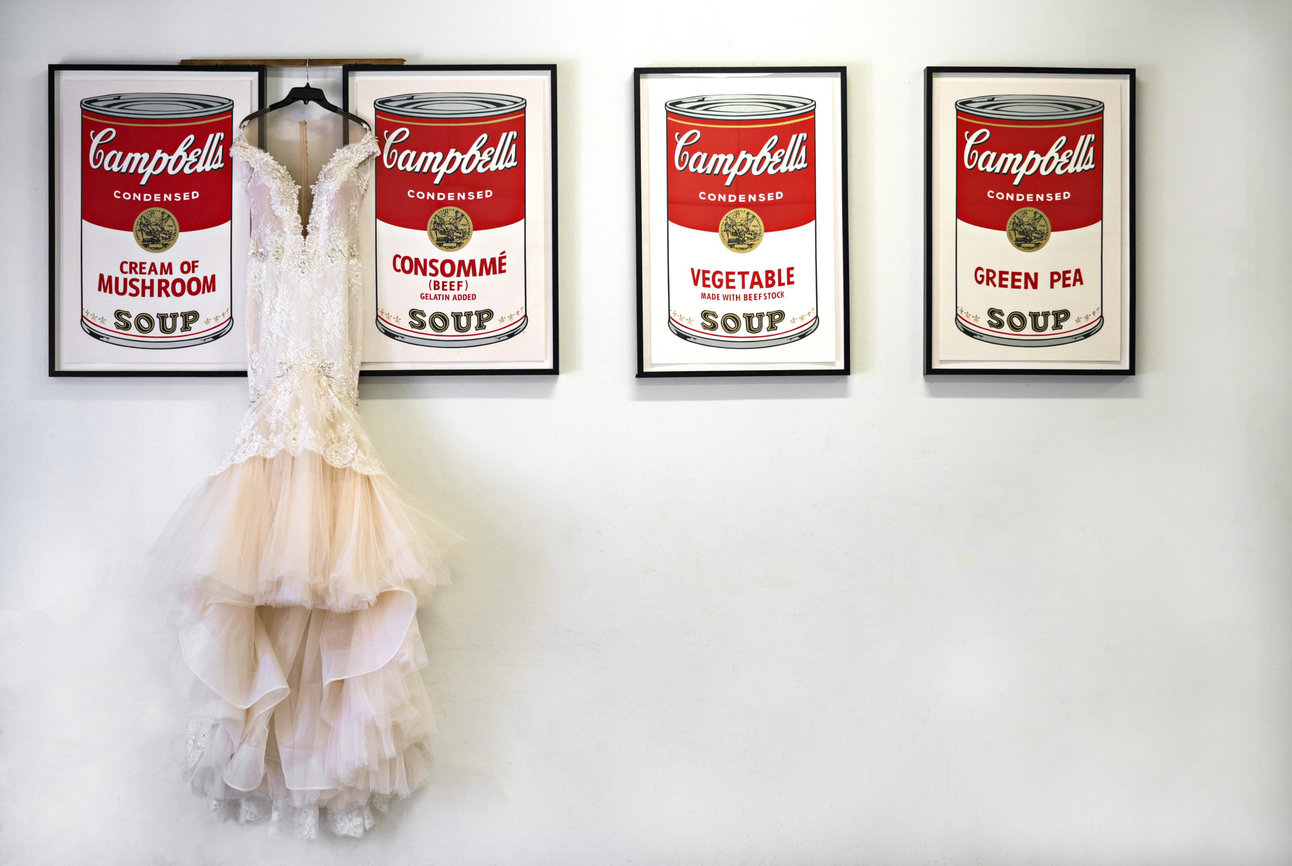Wedding dress displayed above four Andy Warhol soup-can prints at Aria in Minneapolis