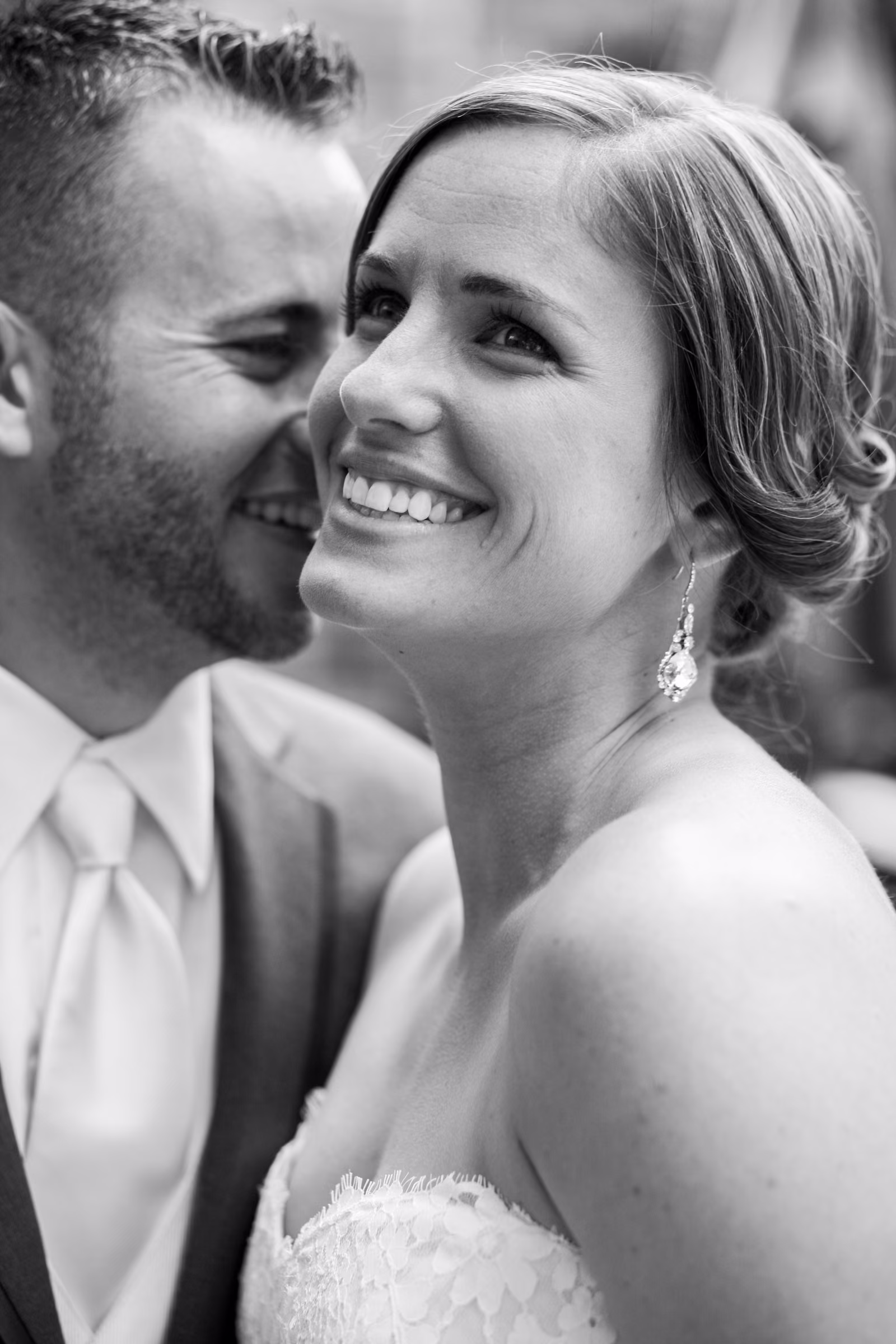 Annie smiles while Matt kisses her cheek in a close black and white portrait