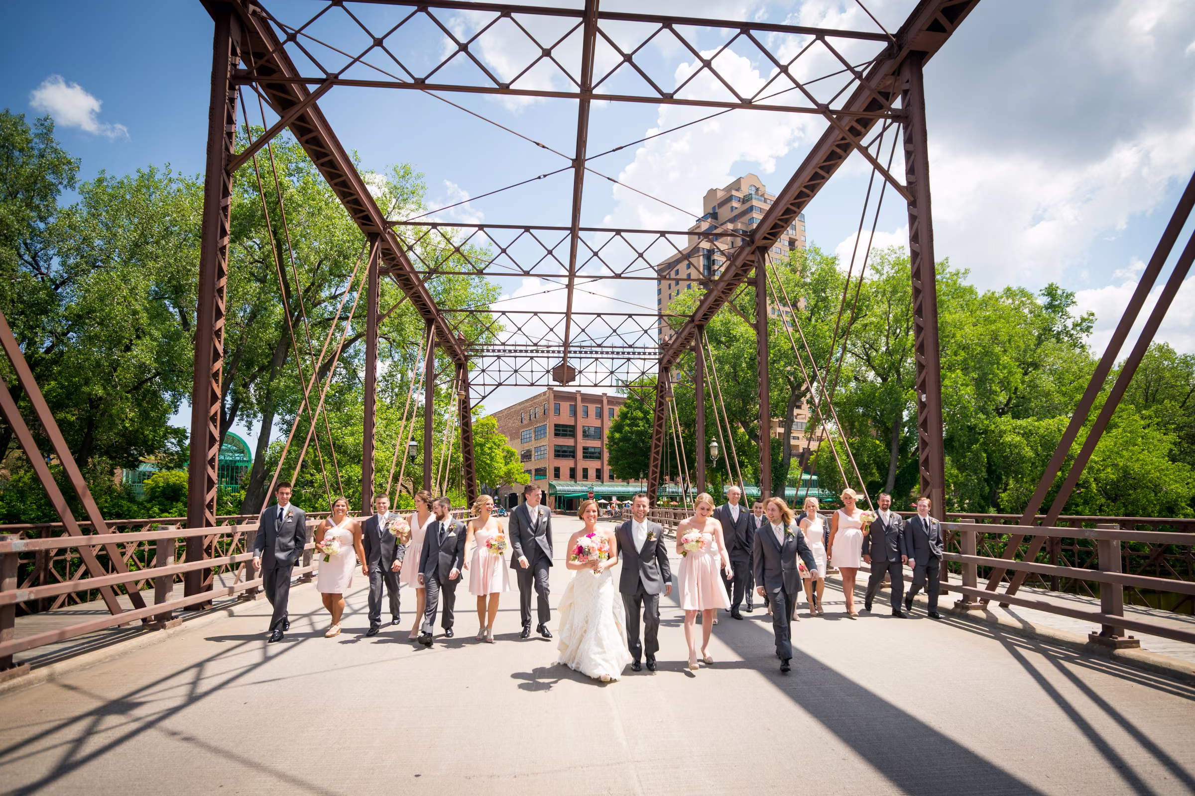Matt and Annie walk with their wedding party beneath the trusses of Merriam Street Bridge
