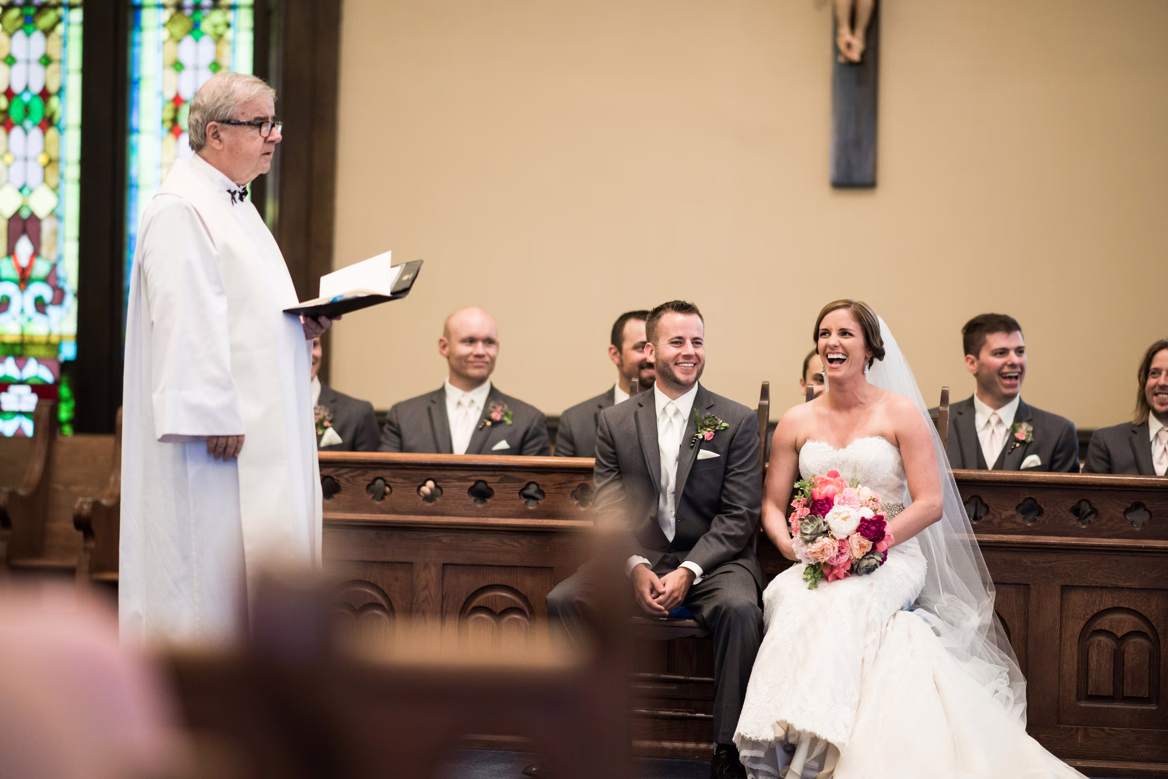 Annie, Matt, and members of the wedding party laugh during the church ceremony