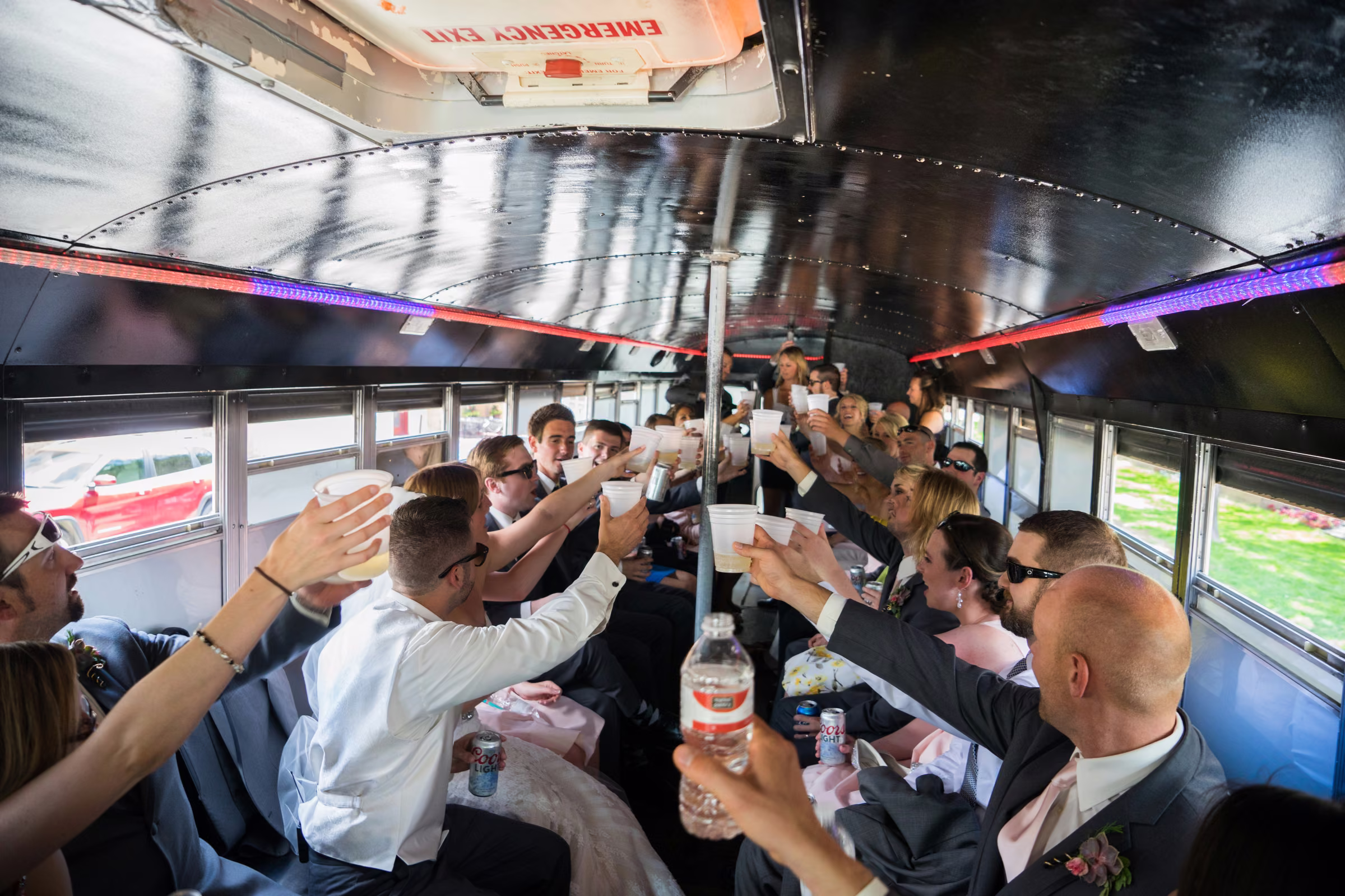 The wedding party raises drinks together inside the bus