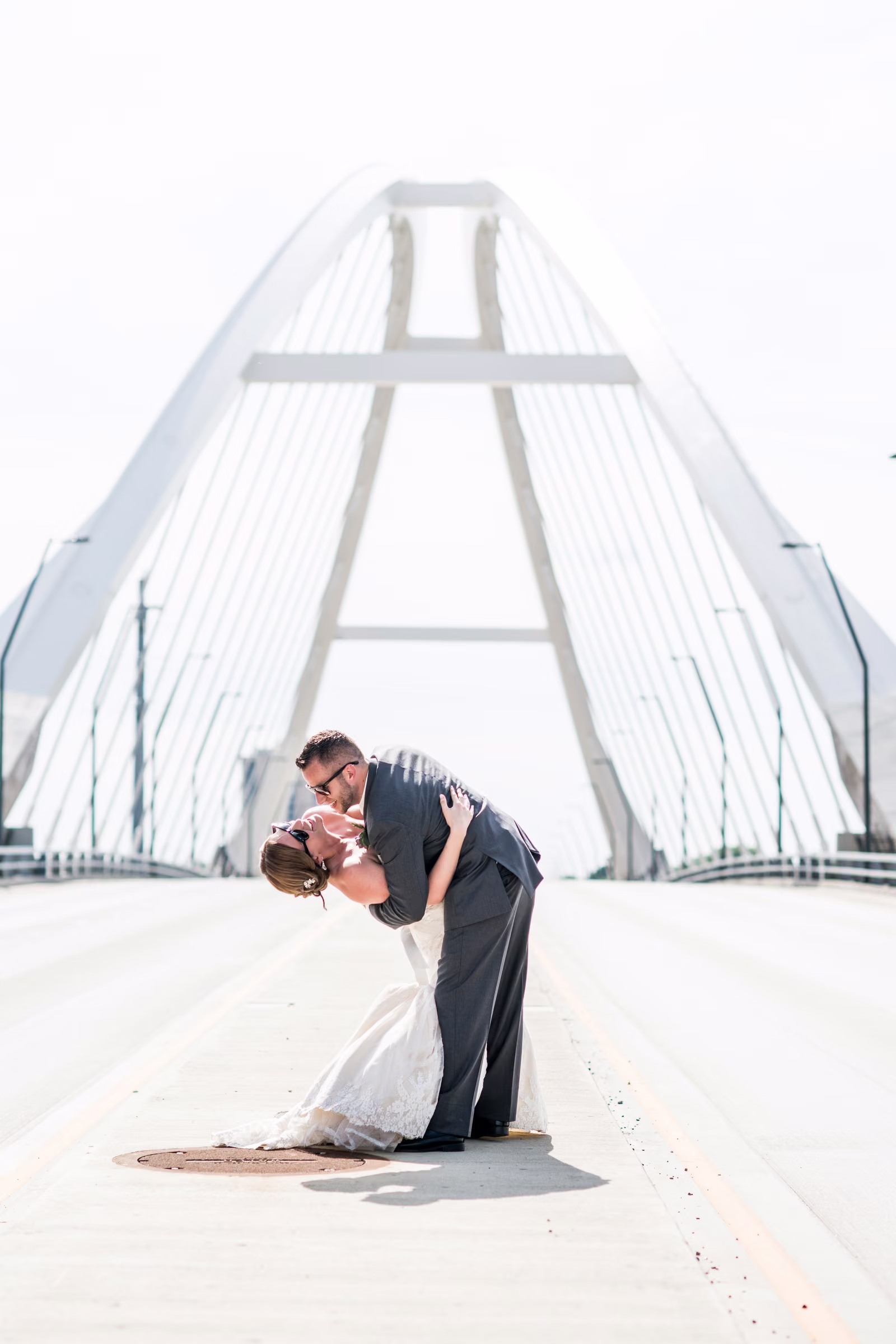 Matt dips Annie for a kiss beneath the pale arch and cables of Lowry Avenue Bridge