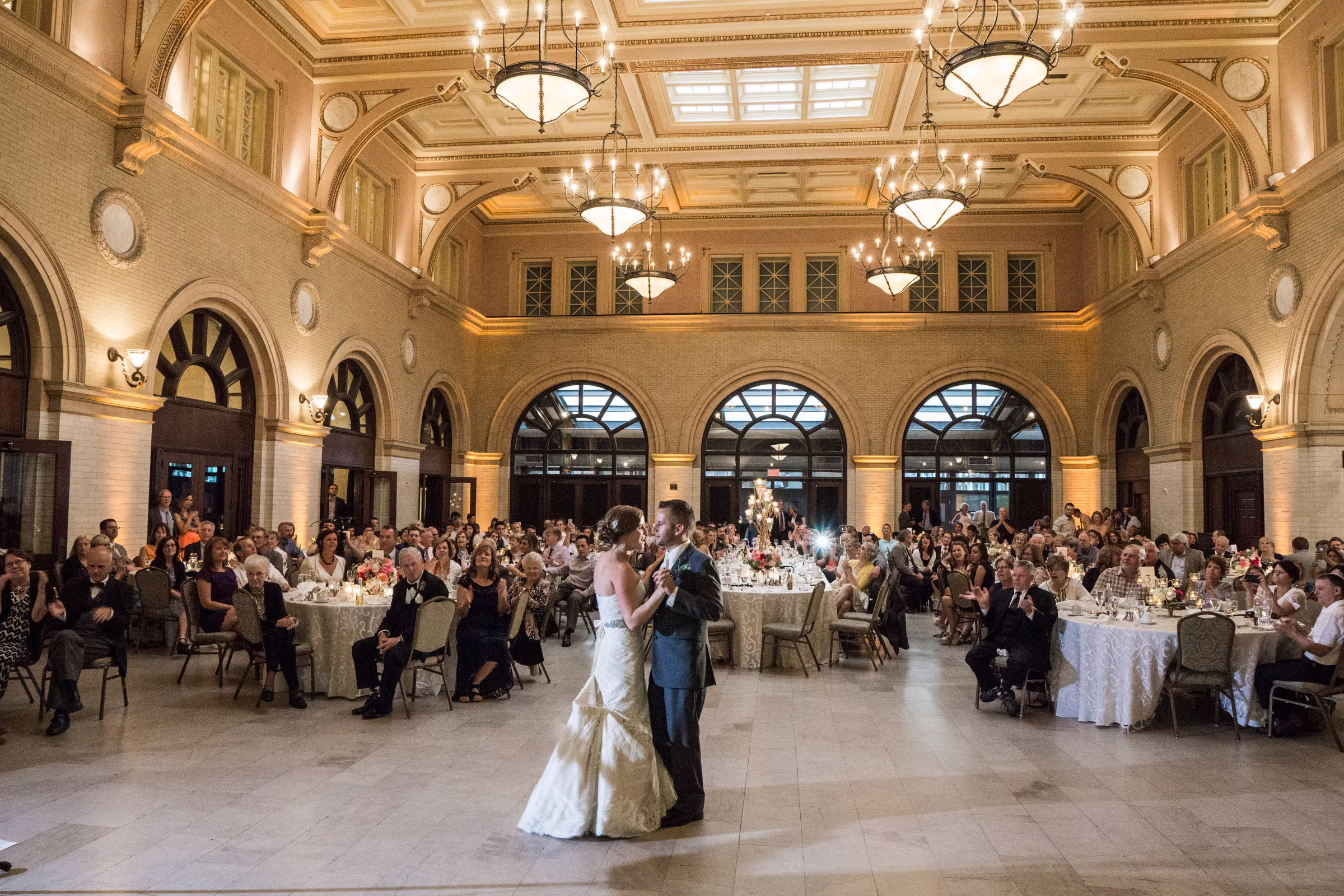 Matt and Annie share their first dance beneath chandeliers in the grand reception room at The Depot