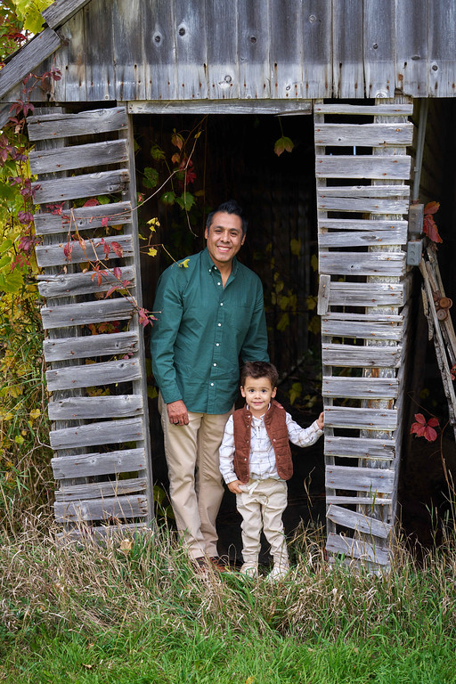 Alberto Zaragoza with his son beside a weathered barn at Minnesota Landscape Arboretum, Chaska, Minnesota