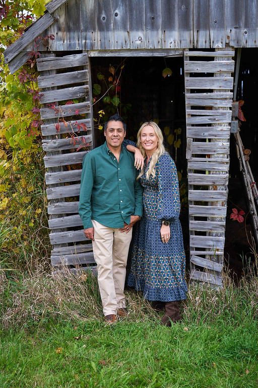 Carrie and Alberto Zaragoza together beside a weathered barn at Minnesota Landscape Arboretum, Chaska, Minnesota