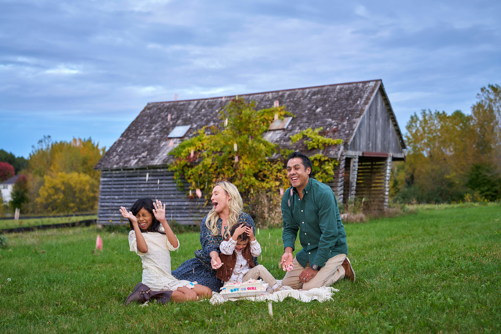 The Zaragoza family tossing cake into the air beside a weathered barn at Minnesota Landscape Arboretum, Chaska, Minnesota