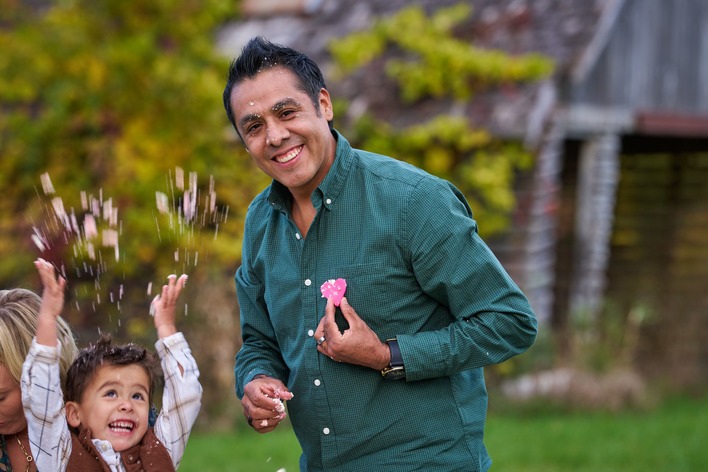 Alberto Zaragoza holding a pink cake decoration as his young son plays beside him at Minnesota Landscape Arboretum, Chaska, Minnesota