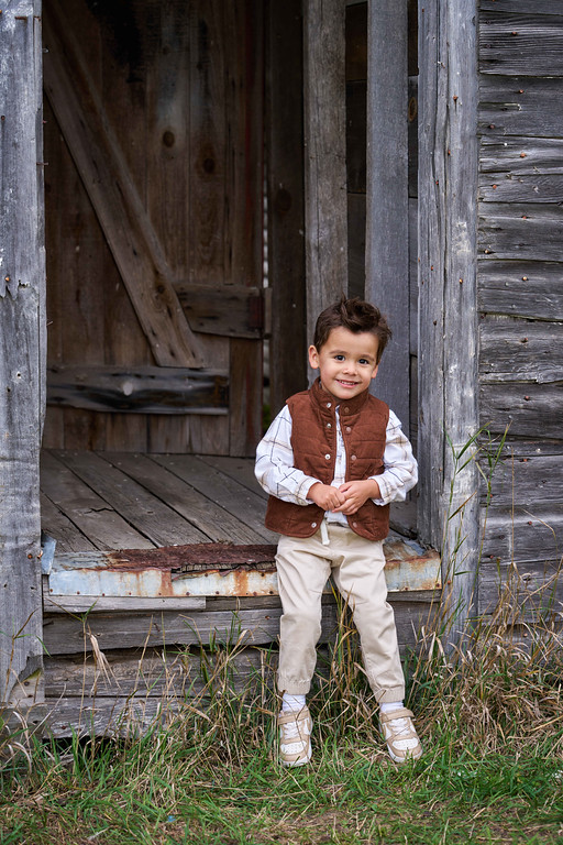 A young Zaragoza boy standing in a weathered barn doorway at Minnesota Landscape Arboretum, Chaska, Minnesota